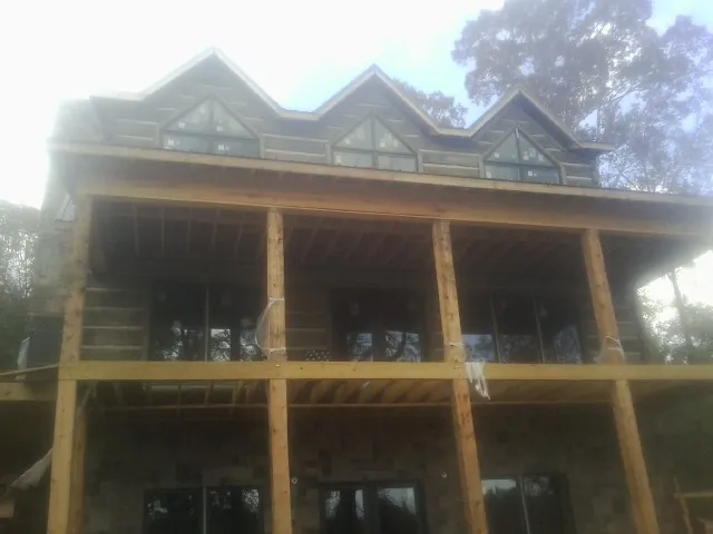 Dormers and porch framing on a large log home under construction — Roof Coating work by our crew in Lincolnshire