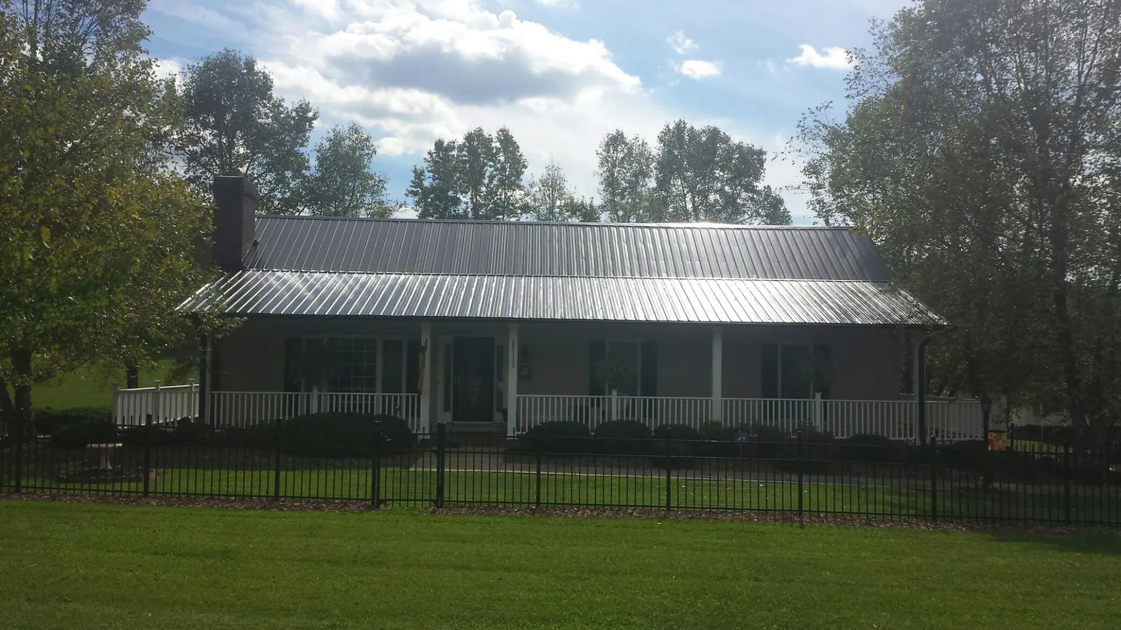 Gray metal roof on a brick ranch with a full width front porch — Gutter Guard Installation work by our crew in Lincolnshire