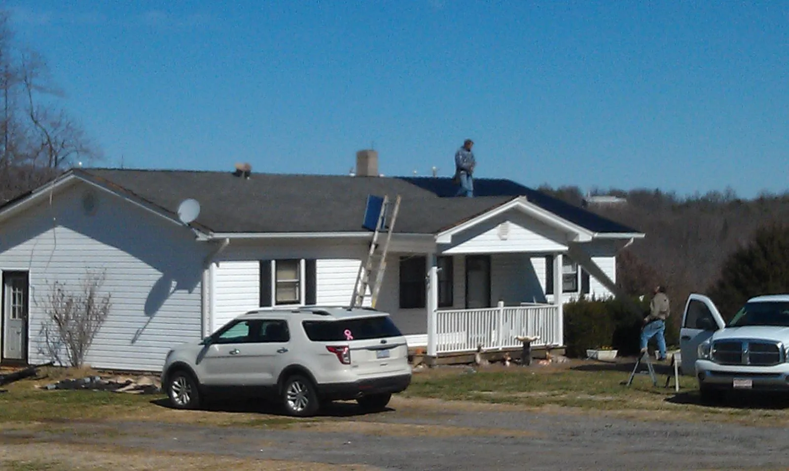 Roofers stripping shingles from a white ranch house roof in Lincolnshire
