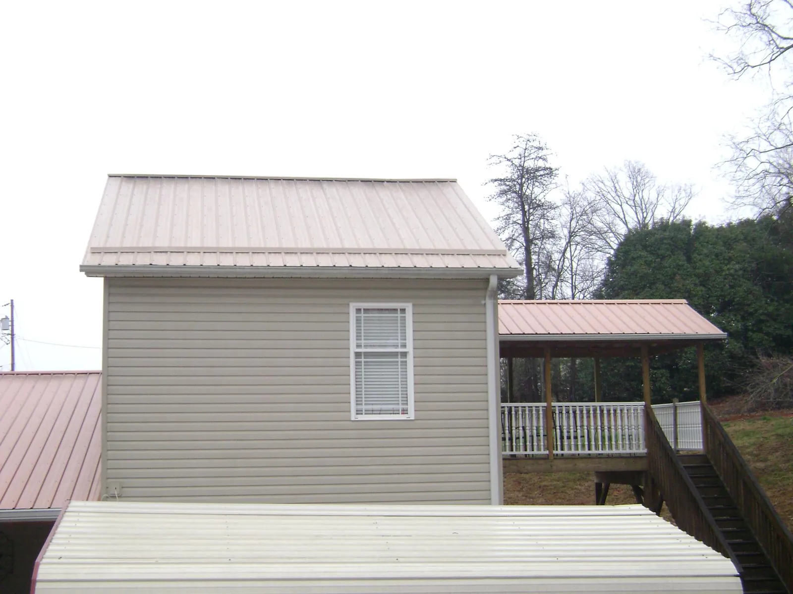 Tan metal roofs on a two story addition and attached porch, from a Roof Replacement job in Lincolnshire